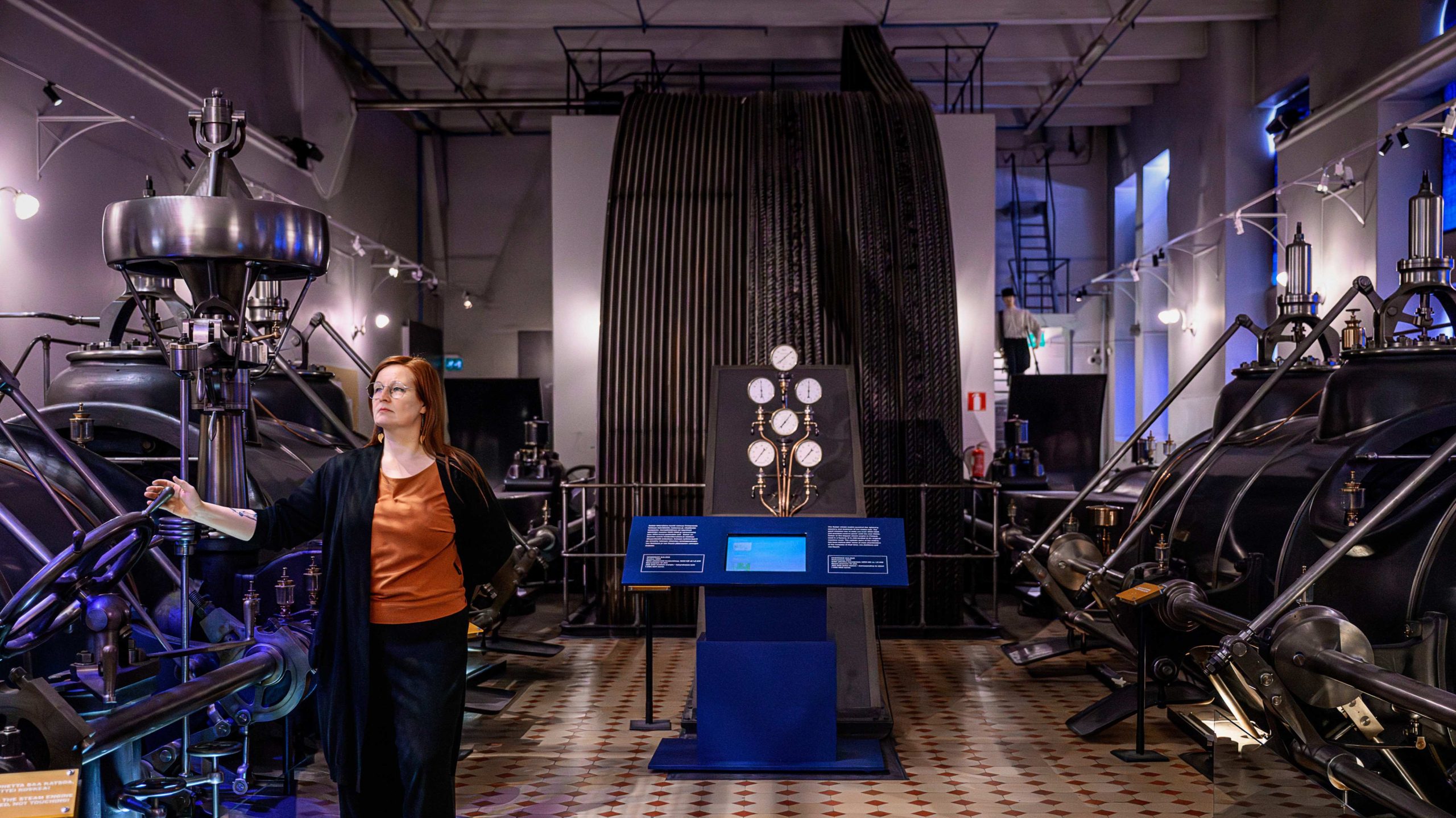 Det står ett enormt ångkraftverk i den nästan oförstörda fabriksbyggnaden. Ångmaskinen som Ulla Rohunen visar upp var en gång Finlands största.Foto: Cata Portin